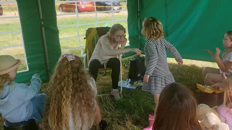 Joanne Marr in a tent making funny faces while telling a story to children